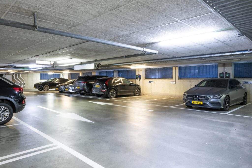 Ondergrondse parkeergarage aan het Koningin Wilhelminaplein met geparkeerde auto's en oplaadpunten voor elektrische voertuigen.